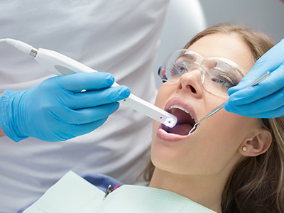 A dental professional using a device to clean a patient s teeth in a dental office.