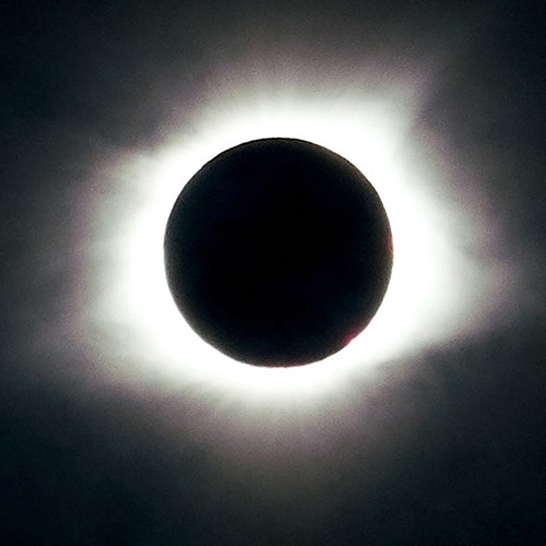 An eclipse of the moon, with the moon appearing as a dark circle against a cloudy sky.