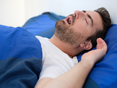 The image shows a man lying in bed with his eyes closed, suggesting he is asleep.