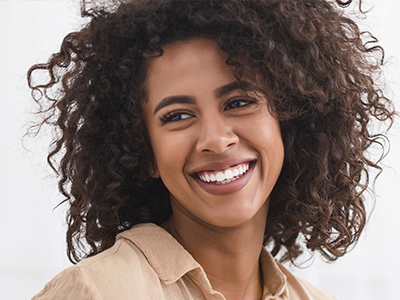 A woman with curly hair and a radiant smile, looking directly at the camera.